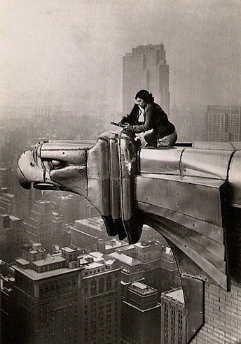 Archival image of photographer Margaret Bourke-White sitting on the eagle head gargoyle of The Chrysler Building in New York City.